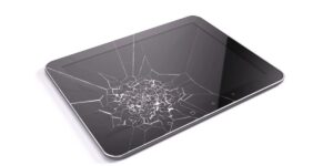 Tablet lying flat with a large central shatter forming a spiderweb pattern across the glass surface