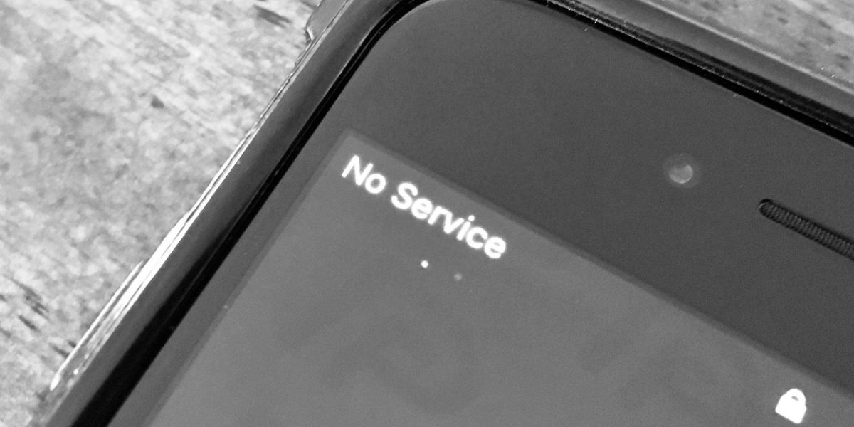 Close-up, black and white photo of a smartphone screen displaying the text "No Service" in the upper left corner