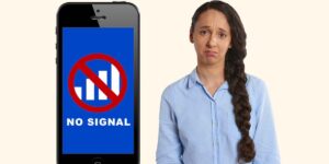 Disappointed woman standing next to a smartphone displaying a blue screen with a "NO SIGNAL" warning and a red circle